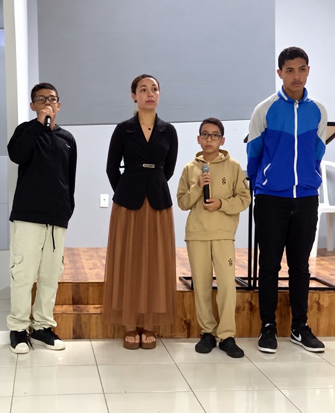 Quatro pessoas reunidas na igreja, duas delas com microfones